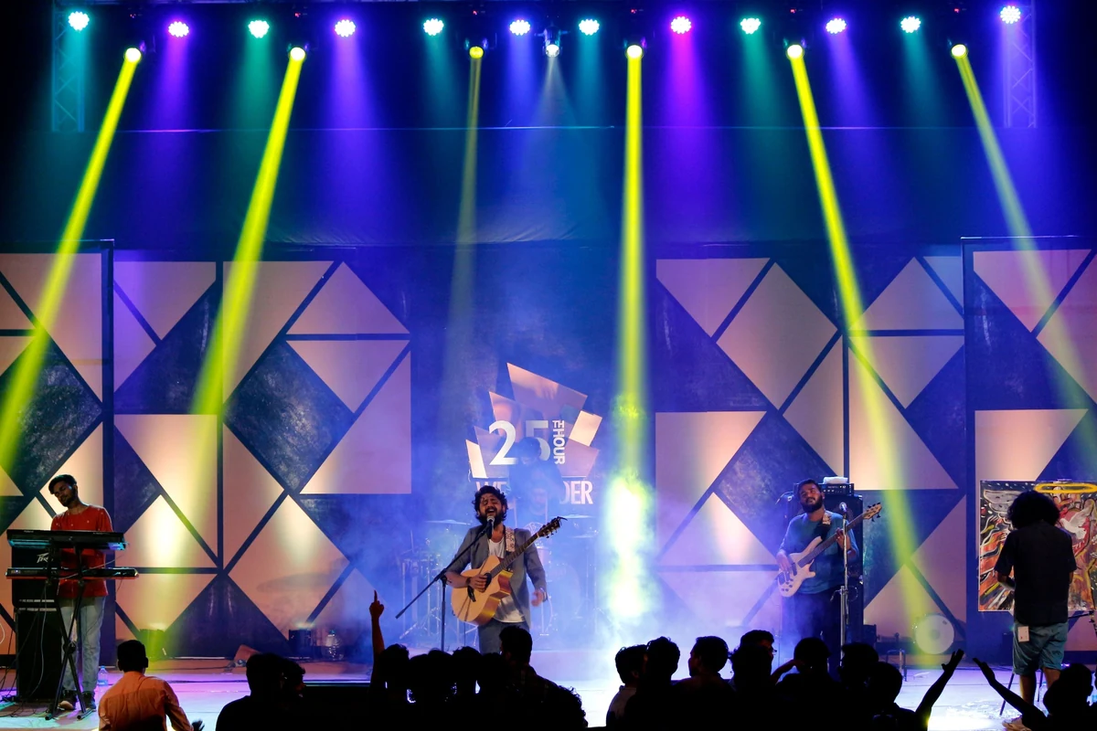 Live band performing on a stage with coloured light beams