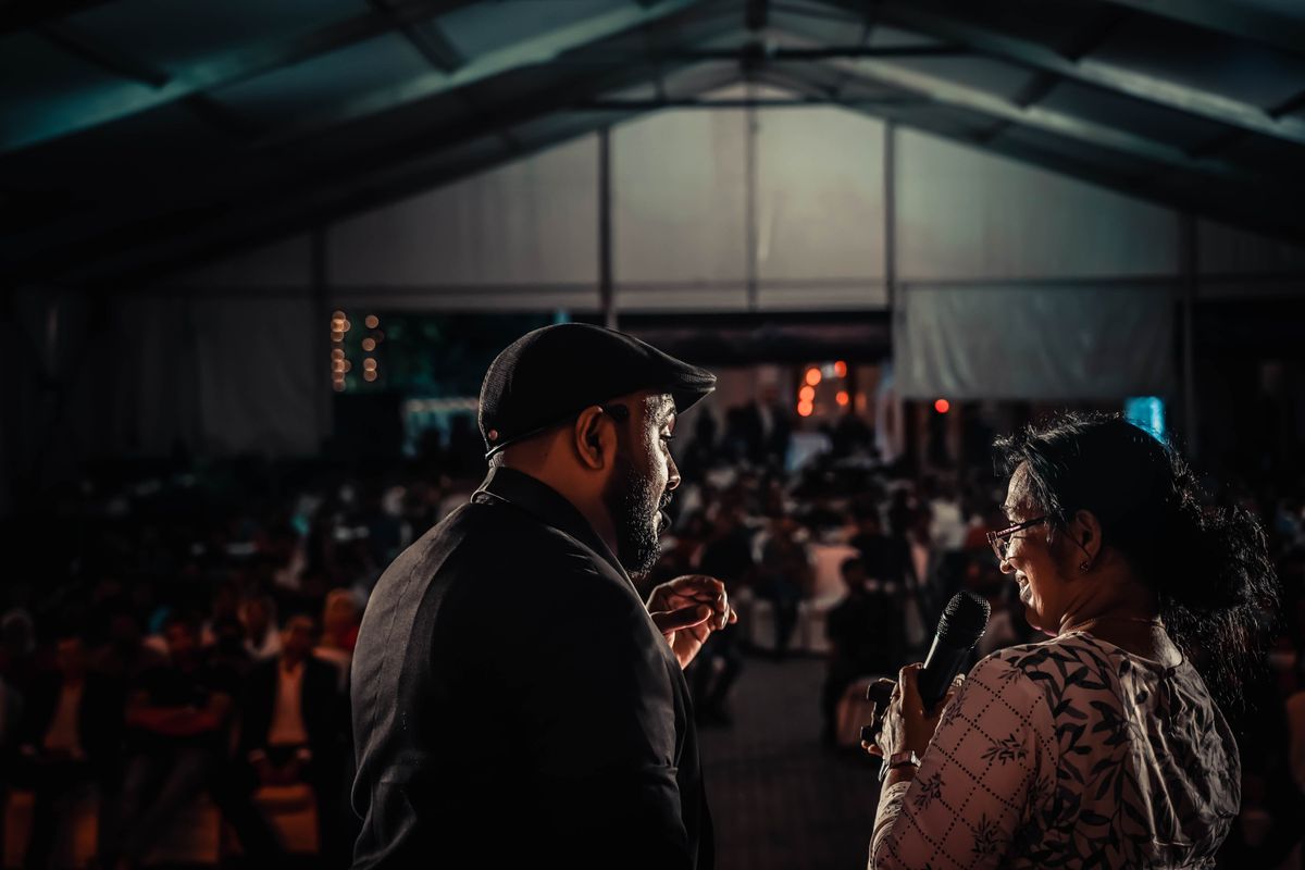 Host holding a microphone among guests at an indoor event